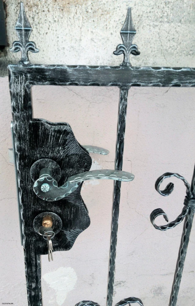 Detail zámku s kľučkou a kľúčom na kovanej bráničke